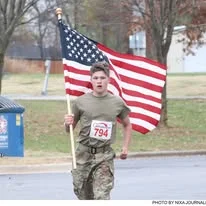 A soldier carrying the American flag along the route